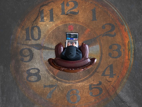 A student typing while in the middle of a ticking clock.